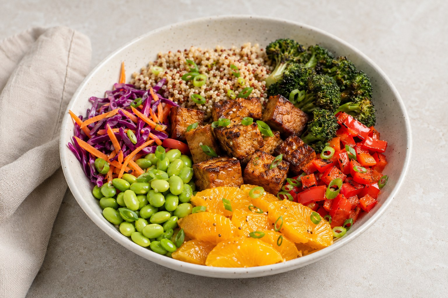 Colorful tempeh and edamame power bowl with quinoa, vegetables and orange segments